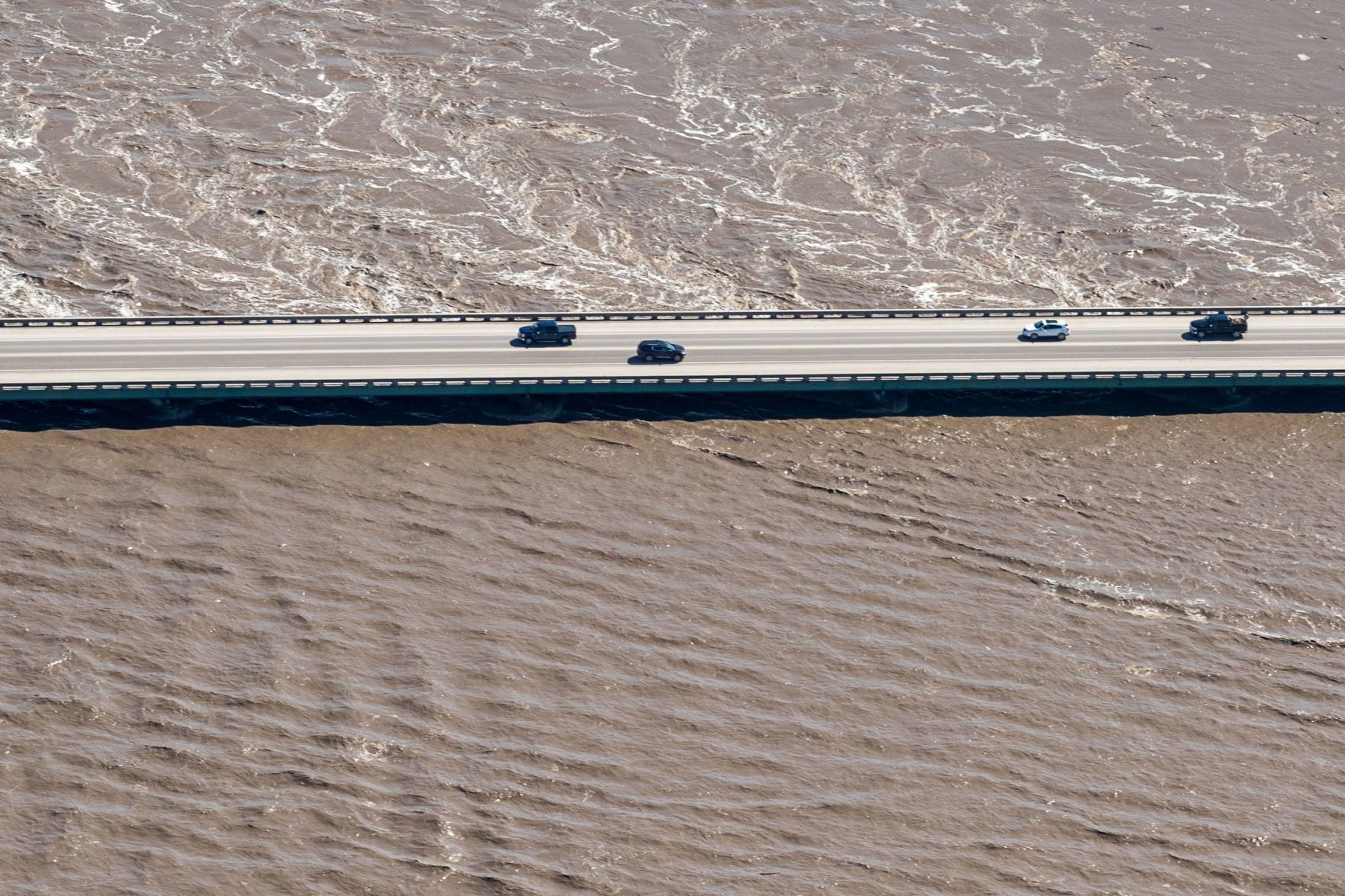 Cars drive drive across a flooded Platte River on Highway 50 just north of Louisville.